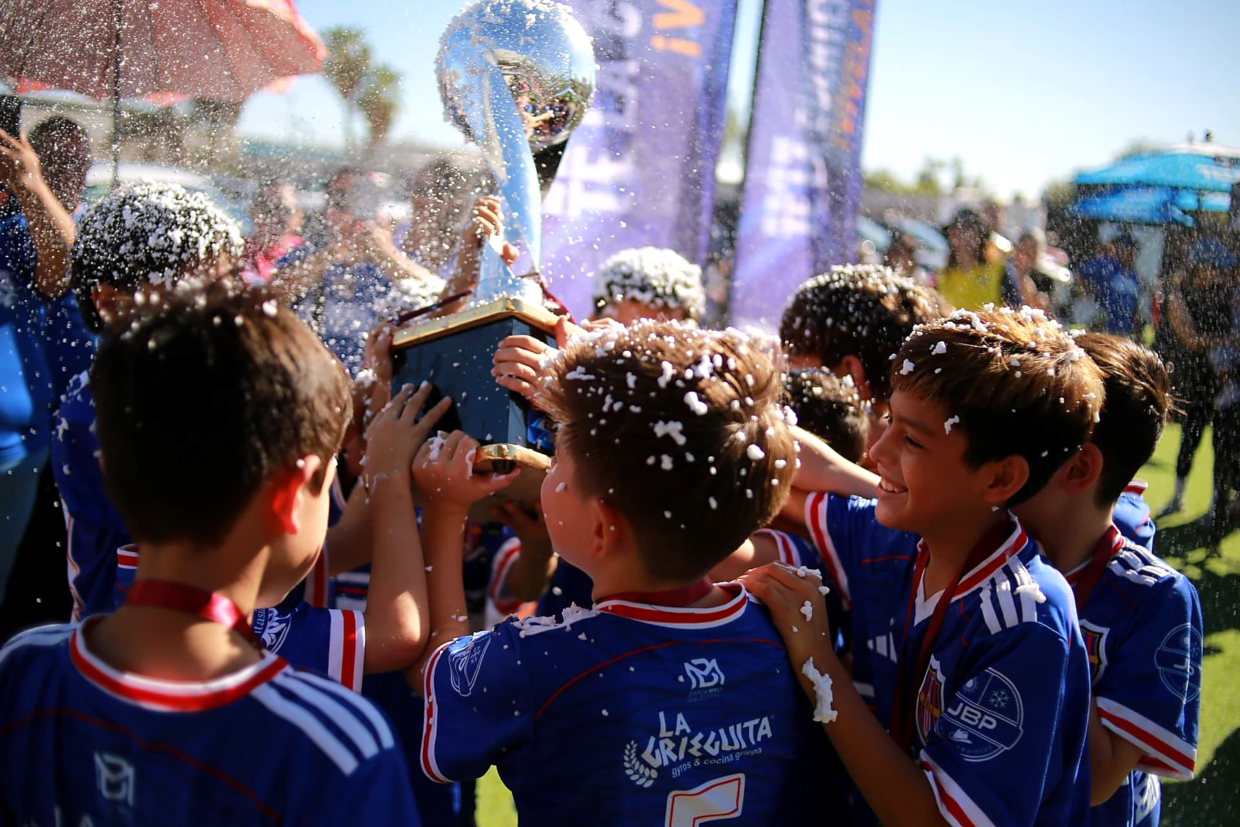 Equipo infantil celebrando con un trofeo en Distrito Sports